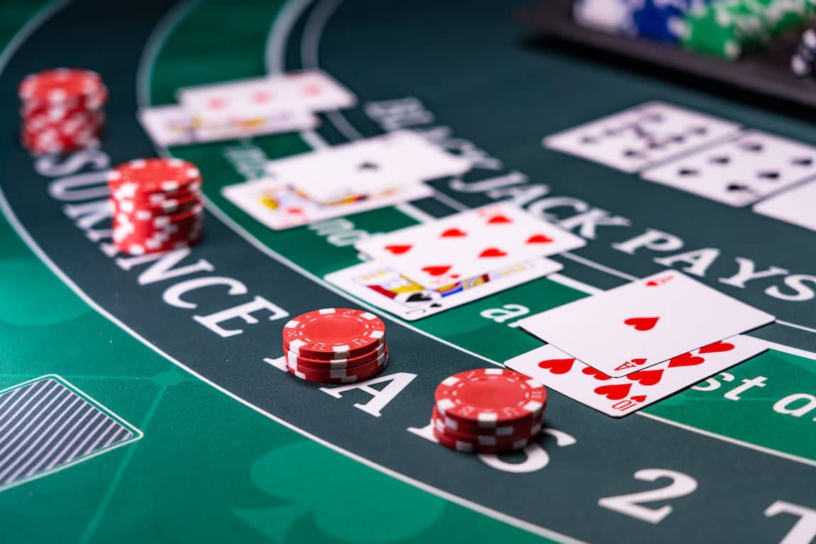 Mesa de blackjack com cartas e fichas representando a ação de dobrar a aposta durante o jogo.