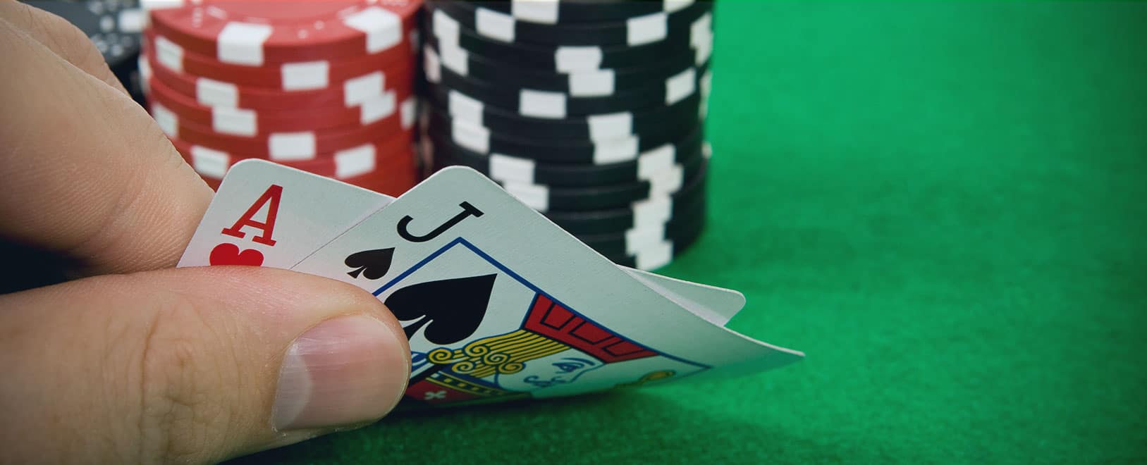 Contagem no blackjack. jogador segurando cartas de blackjack com fichas de cassino ao fundo.